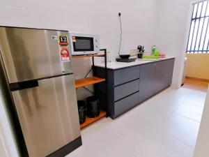 a kitchen with a stainless steel refrigerator and a microwave at The Foreigner Staycation at Riverine Diamond Kuching in Kuching