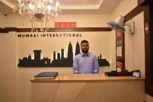 a man standing at a counter in an office at Hotel Mumbai International- Near T2 International Airport in Mumbai
