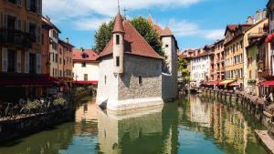 ein Fluss mit einer Kirche mitten in einer Stadt in der Unterkunft Les Cordeliers: 2 pers, cosy & cœur vieille ville in Annecy