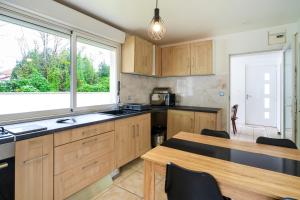 eine Küche mit Holzschränken, einem Tisch und einem Fenster in der Unterkunft Maison 3 chambres jardin 2km plage in Boucau