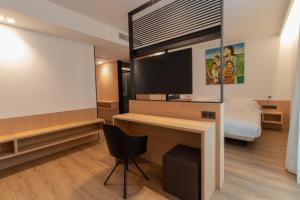 a room with a desk and a bed and a television at Hotel Cortabitarte in Soria