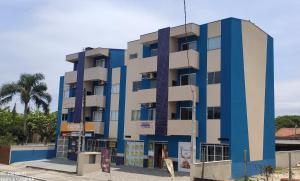 un edificio azul y blanco con una palmera en Residencial Oceano Azul en Itapoa
