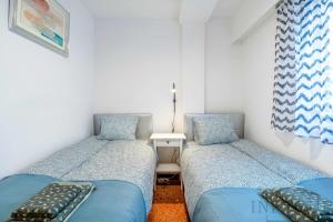 2 łóżka w małym pokoju z niebieskimi łóżkami w obiekcie Inftour Apolo Apartamento w mieście Calpe