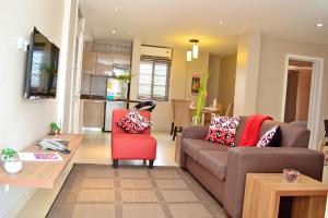 a living room with a couch and a red chair at Acquah Place Residences in Accra