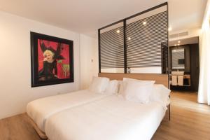 a bedroom with a white bed with a painting on the wall at Hotel Cortabitarte in Soria