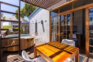 terraza con mesa de madera y bañera en Stone Cottages, en Ciudad del Cabo