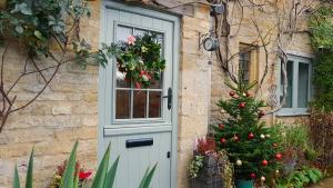 a christmas tree in front of a house with a door at Graziers Cottage - character Cotswold cottage with inglenook, parking and pub nearby in Cheltenham