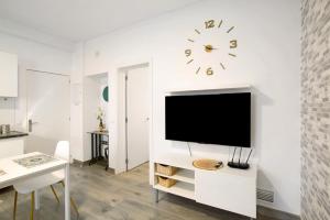 uma sala de estar branca com uma televisão e um relógio na parede em The Greey's House B em Telde