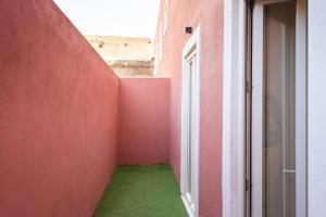 einen leeren Flur mit roter Wand und grünem Boden in der Unterkunft Pardal RC A - Luxury 2 Bed Apartment in Alcantara in Lissabon