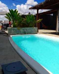 una piscina de agua azul frente a una casa en Casas Peroba Maragogi, en Maragogi