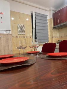 - une table avec des assiettes rouges et des verres à vin dans l'établissement Apartament B Orizont, à Bacău