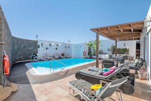 a patio with a pool and chairs and a house at Villa Fae in Playa Blanca