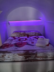 uma cama num quarto roxo com toalhas em LOVE NEST casa vacanze Ercolano em Ercolano