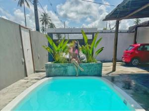 una mujer está sentada junto a una piscina en Casas Peroba Maragogi, en Maragogi