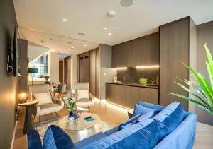 a living room with a blue couch and a kitchen at StayLux Soho in London