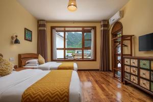 pokój hotelowy z 2 łóżkami i oknem w obiekcie Yangshuo Coco Garden Hotel w mieście Yangshuo