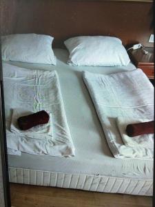 een wit bed met 2 kussens en een afstandsbediening bij Gesztenye apartman in Úrkút