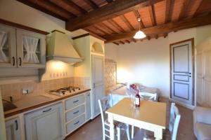 cocina con armarios blancos, mesa y fogones en Residence Borgo Felciaione en Riparbella