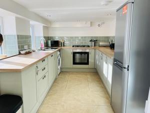 eine Küche mit weißen Schränken und einem Edelstahlkühlschrank in der Unterkunft Lovely Cottage with Mountain Views in Gilwern