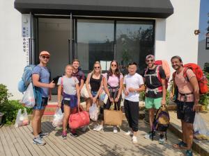 um grupo de pessoas em pé na frente de uma casa segurando sacos em Thirty One em Zhangjiajie