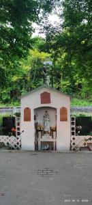 een klein wit gebouw met een standbeeld erin bij Gesztenye apartman in Úrkút