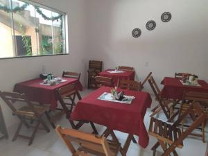 uma sala de jantar com mesas vermelhas e cadeiras de madeira em POUSADA ECOALTER em Santarém