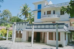 a large white house with a balcony on top at VarkalaEntireHomeKitchenAcRoomsHammocks in Varkala