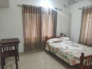 a bedroom with a bed and a table and curtains at VarkalaEntireHomeKitchenAcRoomsHammocks in Varkala