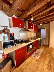 a kitchen with red cabinets and a wooden floor at Appartement Esprit Chalet 71m² in Briançon