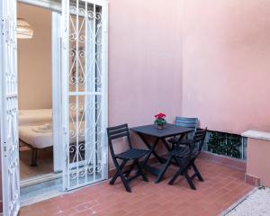 une table et des chaises sur une terrasse avec un mur rose dans l'établissement Residence San Paolo, à Rome