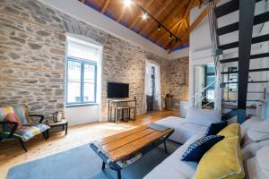 a living room with a stone wall and a couch at PomeGranate Suites in Kavála