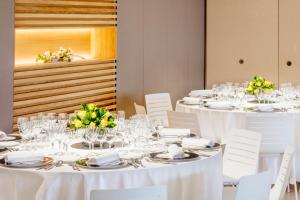 ピネダ・デ・マールにあるAQUA Hotel Promenade & Spa 4Supの白い椅子と白いテーブルクロスが並ぶテーブル
