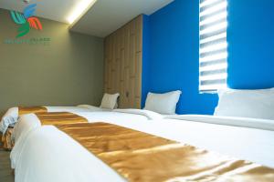a room with two beds and a blue wall at Felicity Island Hotel in Mactan