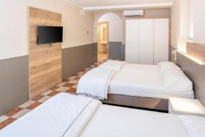 a hotel room with four beds and a flat screen tv at Residenza Panorama in Costermano