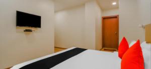 グワーハーティーにあるHOTEL AMBIKA GRANDのベッドルーム(赤い枕のベッド1台、テレビ付)