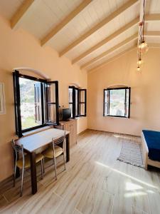 een woonkamer met een tafel, stoelen en ramen bij Pavlos House in Symi