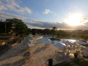 ein Resort mit Pool, Sonnenschirmen und Tischen in der Unterkunft Flat Winterwille Gravatá in Gravatá