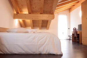 sypialnia z białym łóżkiem i drewnianym sufitem w obiekcie Hotel Milano w mieście Tione di Trento