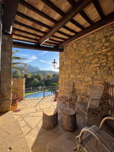 a patio with two chairs and a stone wall at Cal Poldo in Marganell