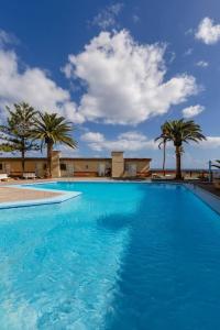 een groot blauw zwembad met palmbomen op de achtergrond bij Atlantic Pearl in Candelaria