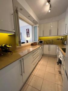 a kitchen with white cabinets and a yellow wall at Cosy three bedroom bungalow in Costa Adeje in Adeje