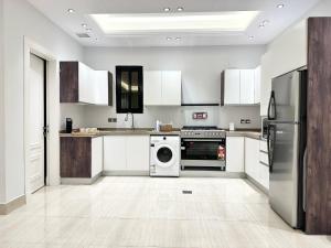 a kitchen with white cabinets and a washer and dryer at Luxurious 3 Bedroom Apartment - 5 minutes to Boulevard in Riyadh