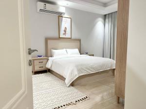 a white bedroom with a bed and a window at Luxurious 3 Bedroom Apartment - 5 minutes to Boulevard in Riyadh