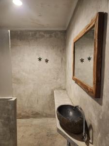 uma casa de banho com um lavatório de pedra e um espelho. em Bagus Ink Surf Camp em Uluwatu