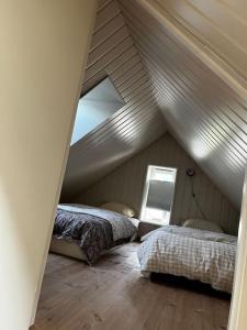 a attic room with two beds and a window at Posthuset in Veblungsnes