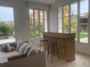 a living room with a couch and a bar with stools at Le Petit Versailles Loire Tours in Rochecorbon