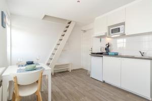 a kitchen with white cabinets and a table and a ladder at Hollandse Nieuwe in Katwijk aan Zee