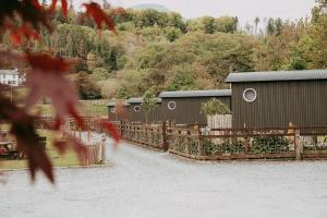 eine Gruppe von Gebäuden mit einem Zaun und Bäumen in der Unterkunft The Wilson Arms in Torver
