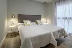 una camera bianca con un grande letto bianco e una finestra di Apartamento rural Las Cañas Esencia de Bardenas a Villafranca