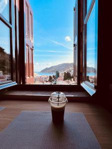 een kopje koffie zittend op een tapijt voor een raam bij Pavlos House in Symi